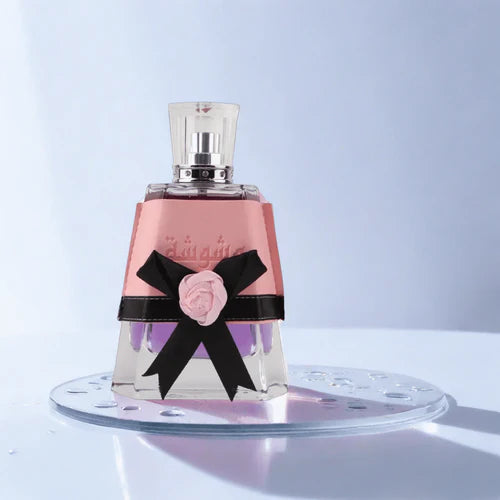 Perfume bottle with pink label and black bow on a light blue background